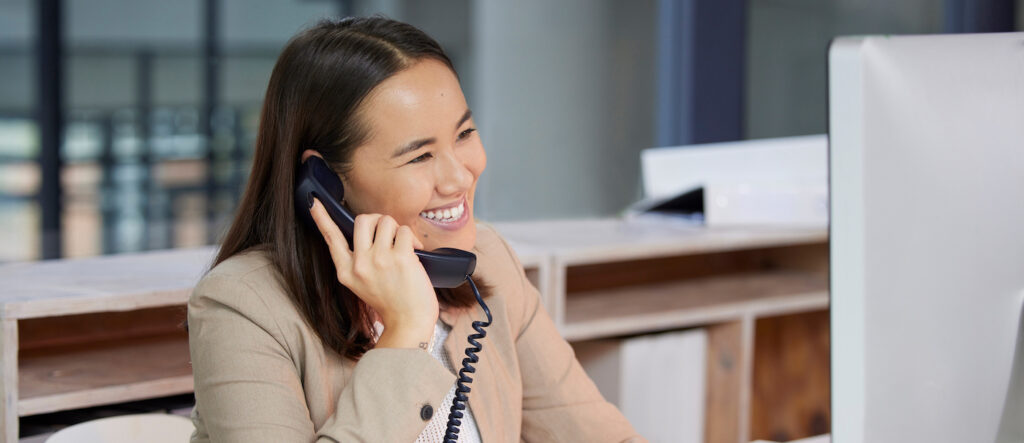 Shot of a young woman using a telephone and computer in a modern office